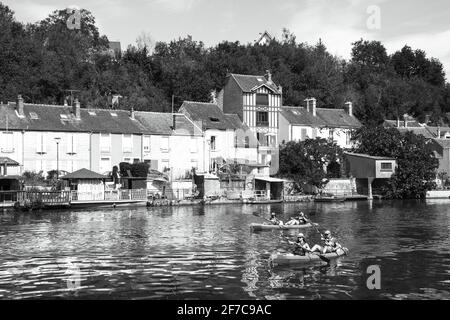 Menschen paddeln Kanu auf Loing Fluss und malerischen Häusern entlang des Wassers. Nemours, Frankreich. Historisches Foto in Schwarzweiß Stockfoto