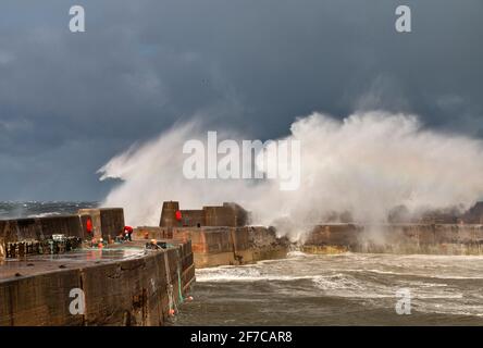 PORTKNOCKIE MORAY COAST SCOTLAND STURM UND SEHR STARKE WINDE WELLEN KRACHEND ÜBER EINEN MANN UND DIE HAFENMAUERN Stockfoto