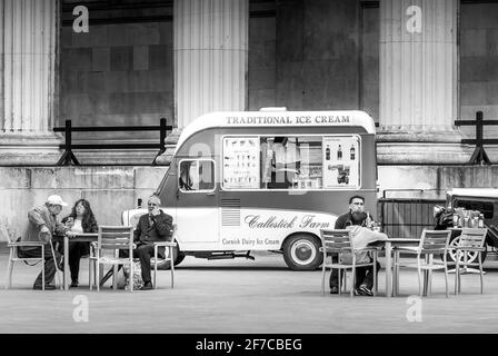 Schwarz-weiß-Szene mit traditionellem Eiswagen und Menschen, die draußen in London sitzen Stockfoto