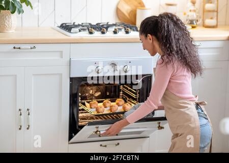 Lächelnd Millennial Weibliche Backen Croissants Im Ofen Zu Hause Stockfoto