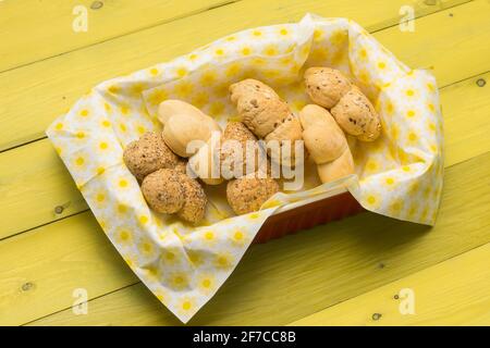 Brötchen in Form einer Blume in bunten Servietten Ein gelber Holztisch Stockfoto