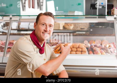 Arbeiten in einer Metzgerei - ein Metzger zeigt Die Vielfalt der Würstchen Stockfoto