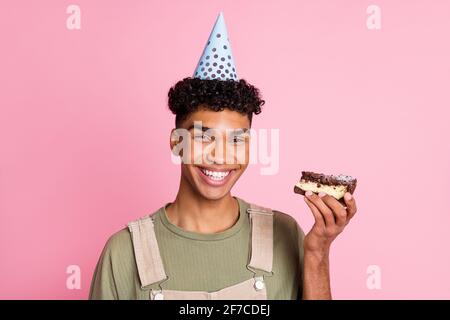 Fotoporträt eines afroamerikanischen Mannes, der Kuchen in der Hand hält Isoliert auf pastellrosa Hintergrund Stockfoto