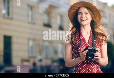 Junge attraktive Studentinnen oder Touristen, die eine spiegellose Kamera benutzen, während sie in der Sommerstadt spazieren gehen. Frau macht Fotos und genießt das Wetter Stockfoto