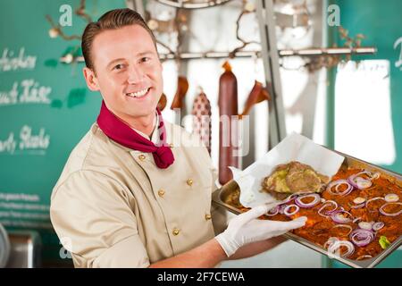 Arbeiten in einem Metzgerladen - ein Metzger mit Grill Steaks Stockfoto