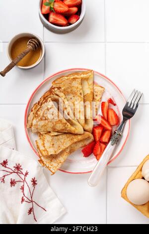 Crepes-Pfannkuchen mit Frischkäse und frischer Erdbeere in schöner weißer Keramikplatte. Platz für Text oder Rezept. Draufsicht Stockfoto