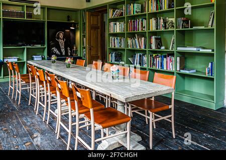 Die Bibliothek des Hotel Renthof in Kassel, Deutschland, ausgestattet mit Literatur über die Documenta-Künstler, bietet Platz für bis zu 20 Konferenzgäste für kreative Arbeit. Grün gestrichene Regale voller Bücher und Kataloge rahmen einen langen Holztisch mit Ledersesseln; anschließend kann hier auch Essen aus dem Restaurant Renthof serviert werden. Stockfoto