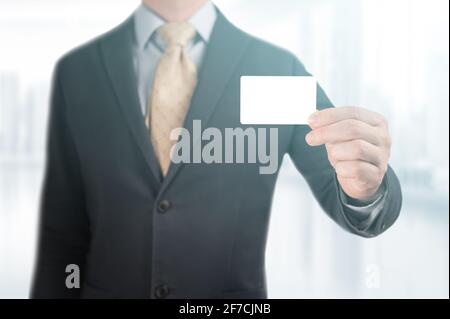 Hand mit leerer Visitenkarte. Hübscher Geschäftsmann in schwarzem Anzug zeigt seine Mockup-Kreditkarte, um eine Zahlung zu machen. Mann mit leerem Bus Stockfoto