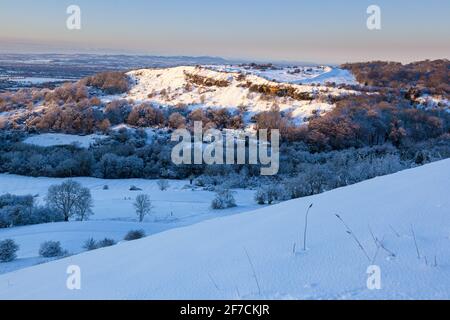 Winterschnee auf Crickley Hill, Gloucestershire UK von Barrow Wake aus gesehen. Es war der Ort von neolithischen Lagerstätten und bronzezeitlichen und eisenzeitlichen Hügelfestungen. Stockfoto