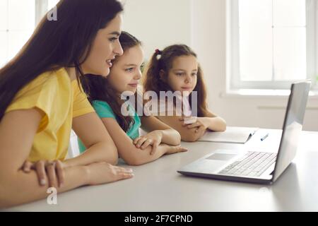 Mutter und Kinder suchen Computer Laptop Bildschirm sitzen zu Hause Blick auf den Schreibtisch Stockfoto
