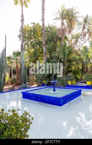 Brunnen in der Villa Majorelle mit ihren umliegenden Palmen und Kakteen im berühmten botanischen Garten Jardin Majorelle in Marrakesch, Marokko Stockfoto