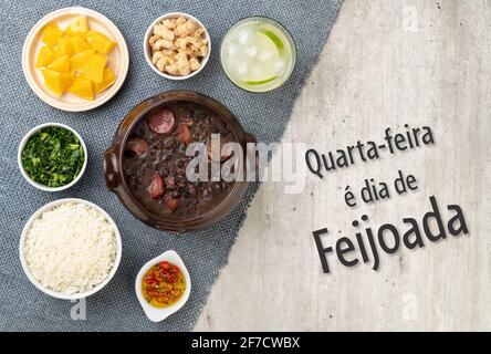 Traditionelle brasilianische Feijoada mit Reis, Grünkohl, Caipirinha. Geschrieben: „Mittwoch ist Feijoada-Tag“ auf portugiesisch. Stockfoto