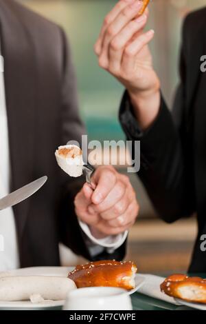 Paar mit traditionellen bayrischen Frühstück in einem Fast-Food-Restaurant, eine Weißwurst mit Brezel Stockfoto