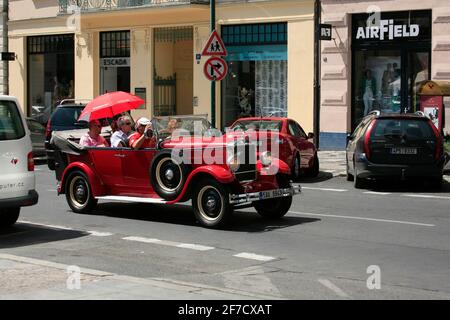 Eine Gruppe von Touristen fährt auf Besichtigungstouren in einem altmodischen Cabrio Stockfoto