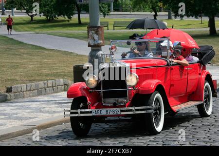 Eine Gruppe von Touristen fährt auf Besichtigungstouren in einem altmodischen Cabrio Stockfoto