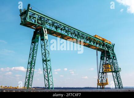 Grüner Portalbrückenkran bei der Arbeit über blauem Himmel Stockfoto