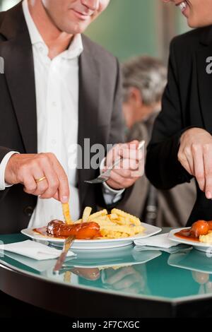 Männliche und weibliche Führungskräfte, die zusammen ein tolles Essen zu sich nehmen Stockfoto