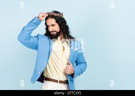 Bärtiger hispanischer Mann lächelt und trägt Krone isoliert auf Blau Stockfoto