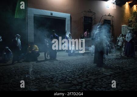 Weihrauch füllt die Straßen nachts, während die Menschen an einer Semana Santa Prozession während der Karwoche in Antigua, Guatemala, teilnehmen. Stockfoto