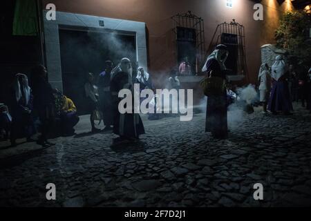 Weihrauch füllt die Straßen nachts, während die Menschen an einer Semana Santa Prozession während der Karwoche in Antigua, Guatemala, teilnehmen. Stockfoto