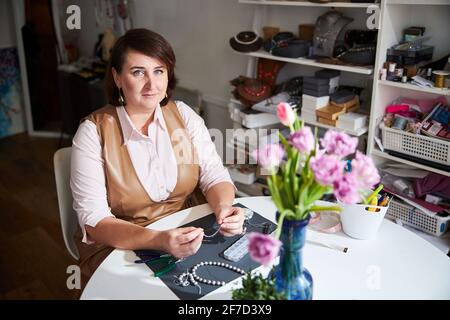 Ruhiger professioneller Juwelier, der für die Kamera am Arbeitsplatz posiert Stockfoto