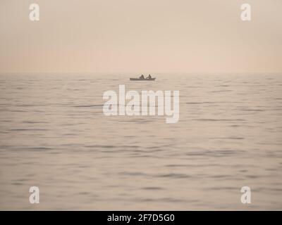 Vintage-Bild mit einem kleinen Fischerboot auf dem Meer. Einsames Boot mitten im Schwarzen Meer Stockfoto