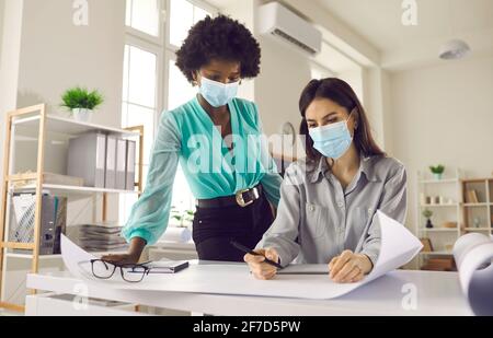 Zwei Geschäftsfrauen, die Gesichtsmasken tragen, arbeiten in ihrem Büro Nach dem Ende der Sperre Stockfoto