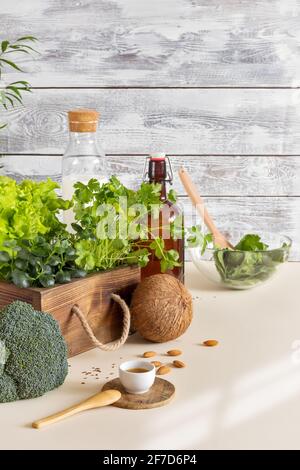 Zusammensetzung von gesunden veganen Lebensmitteln in einer umweltfreundlichen Küche. Natürliches, biologisches, grünes Gemüse, frische Kräuter, Nussmilch auf Holzgrund Stockfoto