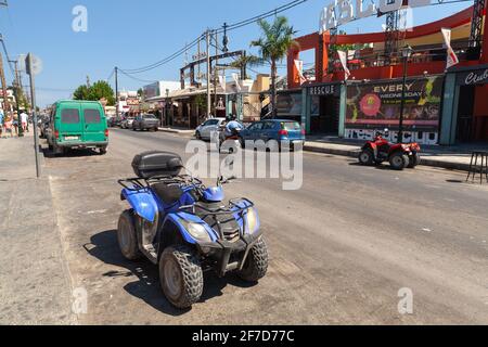 Zakynthos, Griechenland - 14. August 2016: ATV Quad Bike ist auf der Straße von Laganas Resort Stadt geparkt. Gewöhnliche Menschen gehen die Straße entlang Stockfoto