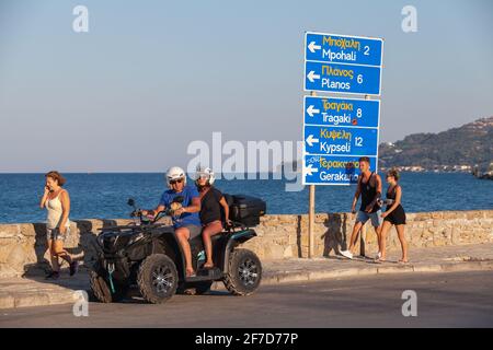 Zakynthos, Griechenland - 14. August 2016: Touristen fahren auf einer Küstenstraße von Zakynthos mit einem Quad-Quad. Ganz normale Menschen gehen in die Nähe Stockfoto