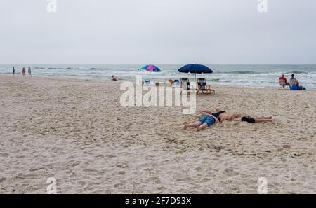 GULF SHORES, AL - 28. MÄRZ 2021: Drei Jungen mit ihren Köpfen im Sand am Strand in Gulf Shores, Alabama, USA Stockfoto