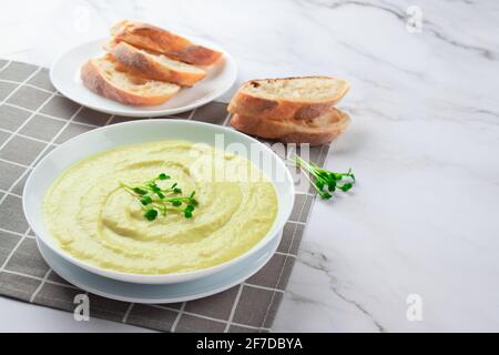 Klassische französische gekühlte Sahnesuppe Vichyssoise - warm oder kalt Kartoffellauch-Suppe mit Mikrogemüse in einer weißen Schüssel garniert Marmortisch Hintergrund und Stockfoto