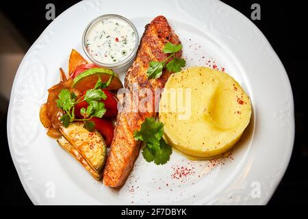 Lachssteak mit gebackenem Gemüse, Kartoffelpüree und Sauce Stockfoto
