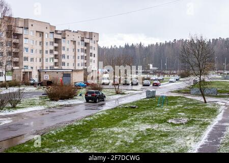 WEISSRUSSLAND, NOVOPOLOTSK - 25. APRIL 2020: Autos auf dem Hof, grünes Gras und Schnee Stockfoto