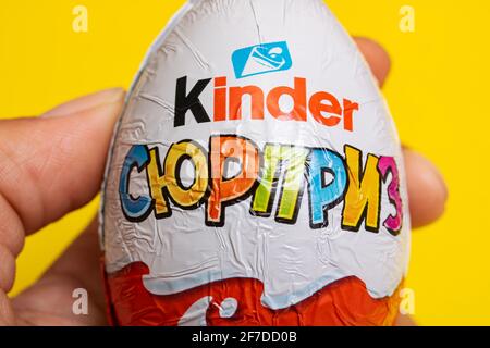 WEISSRUSSLAND, MINSK - 22. JUNI 2020: Kinder überraschen Schokoladenei in der Hand auf gelbem Hintergrund Stockfoto