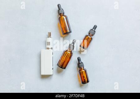 Verdampfer E-Zigarette elektronische Zigarette und flüssige Flaschen auf Beton Stein grauen Hintergrund. Dampfvorrichtung für alternatives Rauchen. Vaping Shop Stockfoto