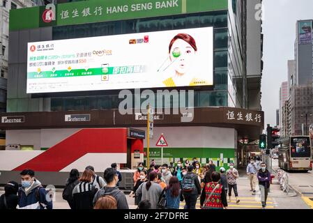 Fußgänger werden gesehen, wie sie die Straße vor der Filiale der Hang Seng Bank in Hongkong überqueren. Stockfoto