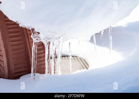 Eiszapfen an einem kalten Wintertag im Südwesten von Ontario, Kanada, roter Backstein im Hintergrund. Stockfoto