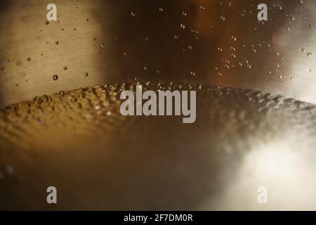 Tibetische Klangschale voller Wasser, Nahaufnahme von Wassertropfen, Klangheilungsinstrument Stockfoto