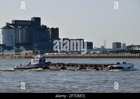 Kleiner Schlepper, der einen Lastkahn die Themse hinunter schiebt London Stockfoto