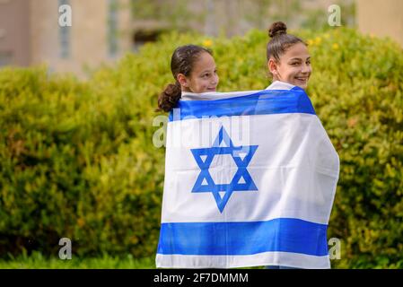 Zwei patriotische jüdische Teenager Mädchen stehen und genießen mit der Flagge Israels auf Natur Hintergrund. Patriotische Feiertag Unabhängigkeitstag Israel - Yom Ha'atzmaut Konzept. Junges Mädchen mit Zahnspangen. Stockfoto