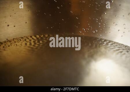 Tibetische Klangschale voller Wasser, Nahaufnahme von Wassertropfen, Klangheilungsinstrument Stockfoto