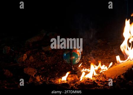 Globe Bleiben Sie auf dem felsigen Boden in der Nähe des flammenden Feuers Stockfoto