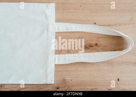 Unbeschriftete Öko-Tragetasche aus Baumwolle auf Holzhintergrund, Design-Mockup Stockfoto