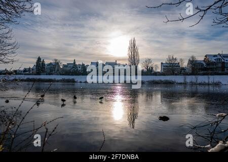 Die Sonne spiegelt sich am schönen gefrorenen Fluss werdersee bei Sonnenschein Warmer weißer Wintertag mit schneebedecktem Deich in bremen Der Abend Stockfoto