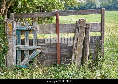 Alter reparierter geschlossener Zaun aus Holz, Stahl und Beton auf dem Land. Bild mit selektivem Fokus. Stockfoto