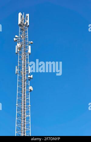 4G- und 5G-Sender auf einem Telekommunikationsturm. Mobilfunkbasisstation mit weißen Sendeantennen auf einem hohen Pol gegen einen blauen Himmel. Stockfoto