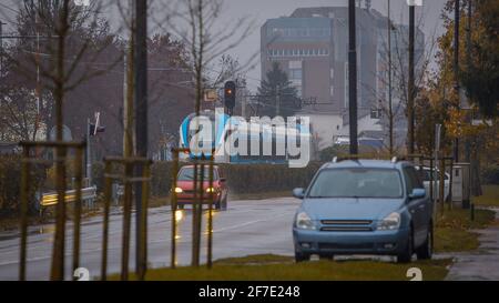 Moderner, weiß-blauer Pendlerzug, der bei Regen vorbeifährt. Bei kaltem und grauem Wetter pendeln Sie mit einem modernen Zug. Stockfoto
