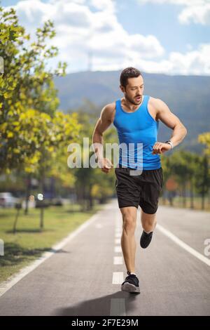 Porträt eines männlichen Läufers in voller Länge, der die Zeit überprüft Ein Laufpfad Stockfoto