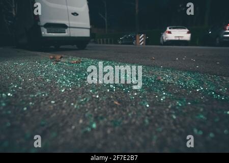 Stücke von gebrochenem grün getöntem Autoglas als Reste eines Einbruchs. Reste eines Einbruchs im Auto, Glasstücke auf der Straße oder auf dem Bürgersteig. Stockfoto